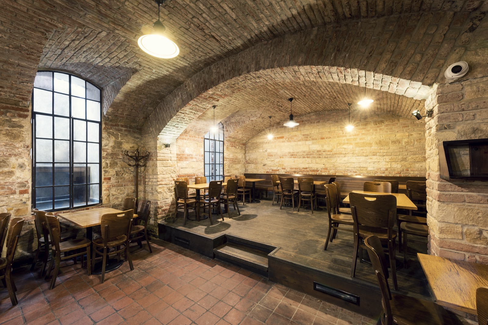 The vaulted room of Pivovarský klub with a long table and a raised platform.